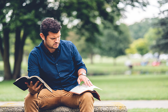 Man reading The Bible in a park